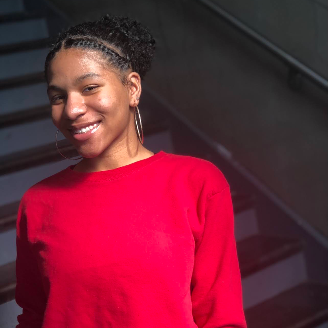 Student Matijanay Tiggle standing in front of stairs in red blouse
